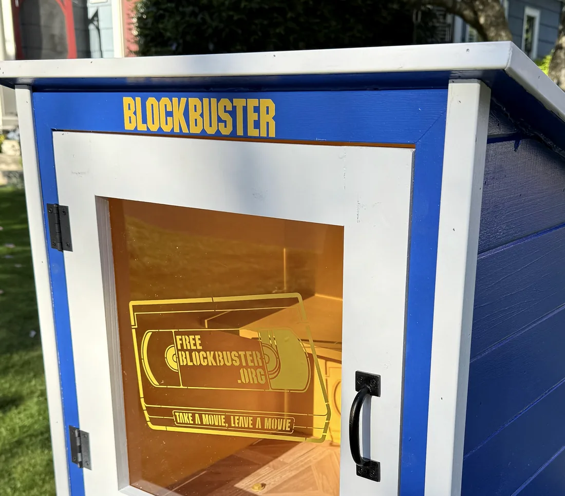 The Free Blockbuster Everett kiosk: a blue and white box on a post with the Blockbuster logo and a Take a Movie, Leave a Movie VHS sticker on the glass door.